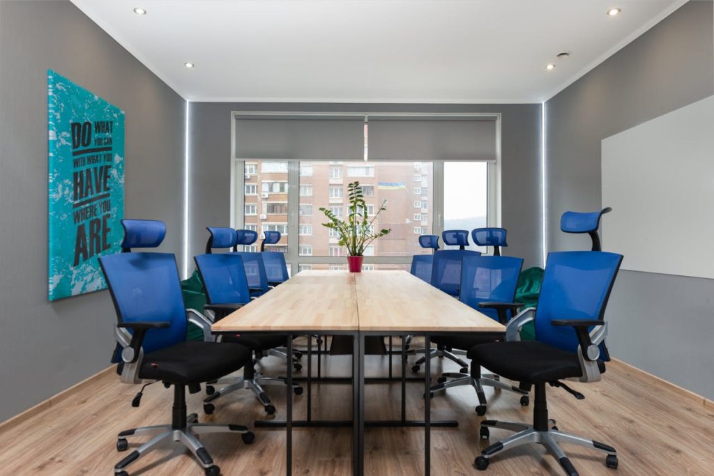 Contemporary office space with blue chairs, table, and motivational quote on the wall.